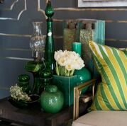 Luscious verdant glass goods surround silk pillows by Alexandra Foster.