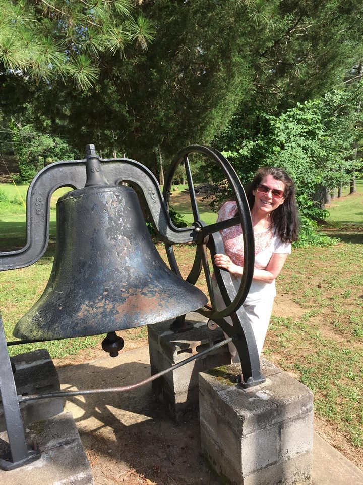 In this photo, Amber posed with the traditional bell used to announce meals, devotionals, class changes and recreation periods at Mid-South Youth Camp.