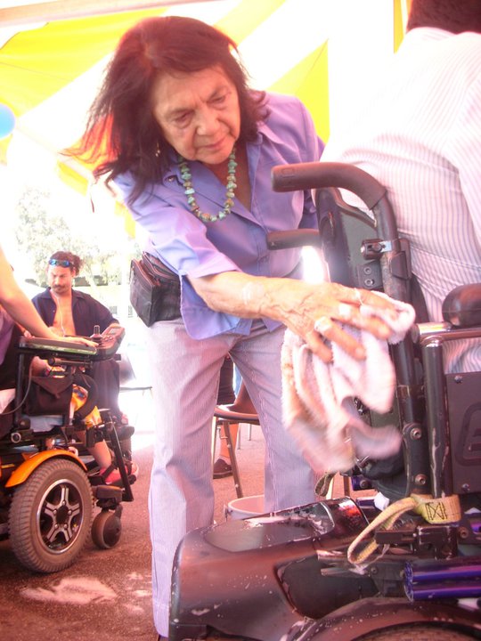 Civil Rights Activists Dolores Huerta washing wheelchairs at a Familia Unida community wheelchair wash.