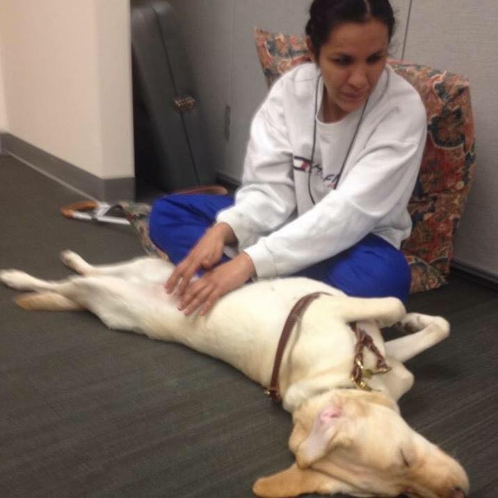 Christella Garcia with her Guide Dog Priscilla doing massage therapy