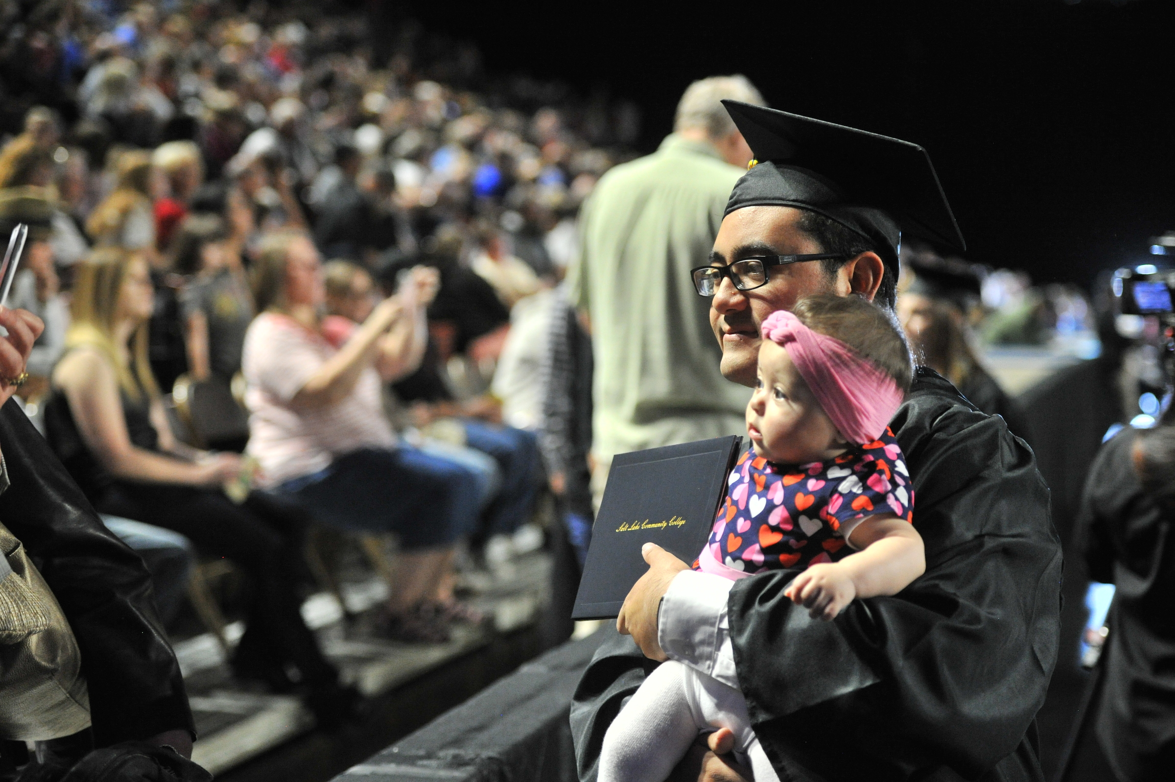 A graduate pauses for a photo with his daughter during the 2016 commencement ceremony for Salt Lake Community College.