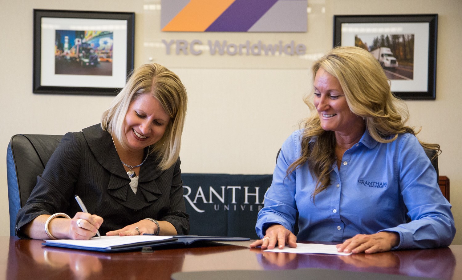 (L to R) Stephanie Fisher, YRC Worldwide Inc. vice president and controller, and Charlyne Valizan, Grantham University national accounts manager, sign a partnership agreement.
