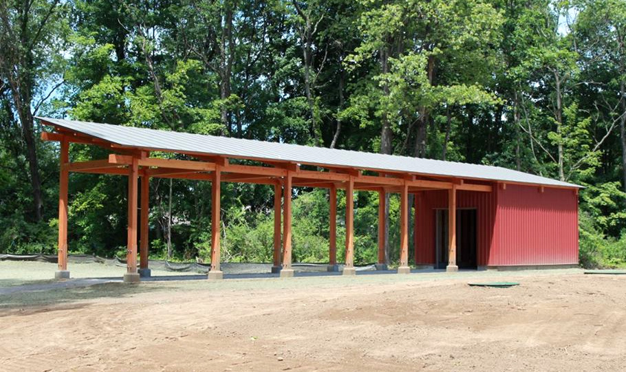 The archery pavilion frame, crafted by New Energy Works Timberframers, is a post-supported rafter frame with structural timber purlins.