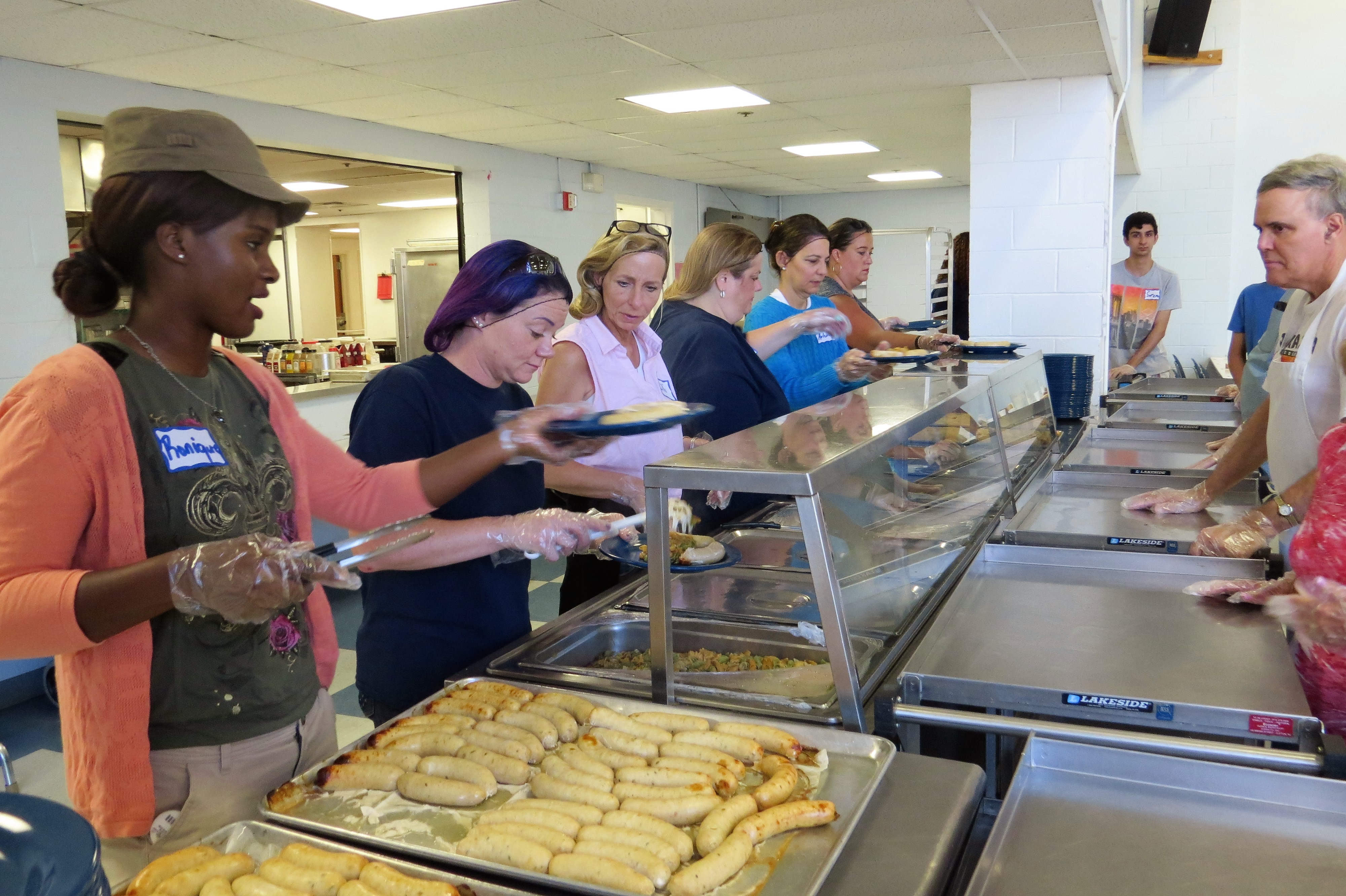 Volunteers from Rapid Pump and Meter Co., gold-level Fund-A-Meal sponsor, help to serve a hot lunch to 400 guests at Eva's Village Community Kitchen.
