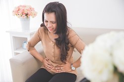 woman holding stomach in pain from hormonal issues