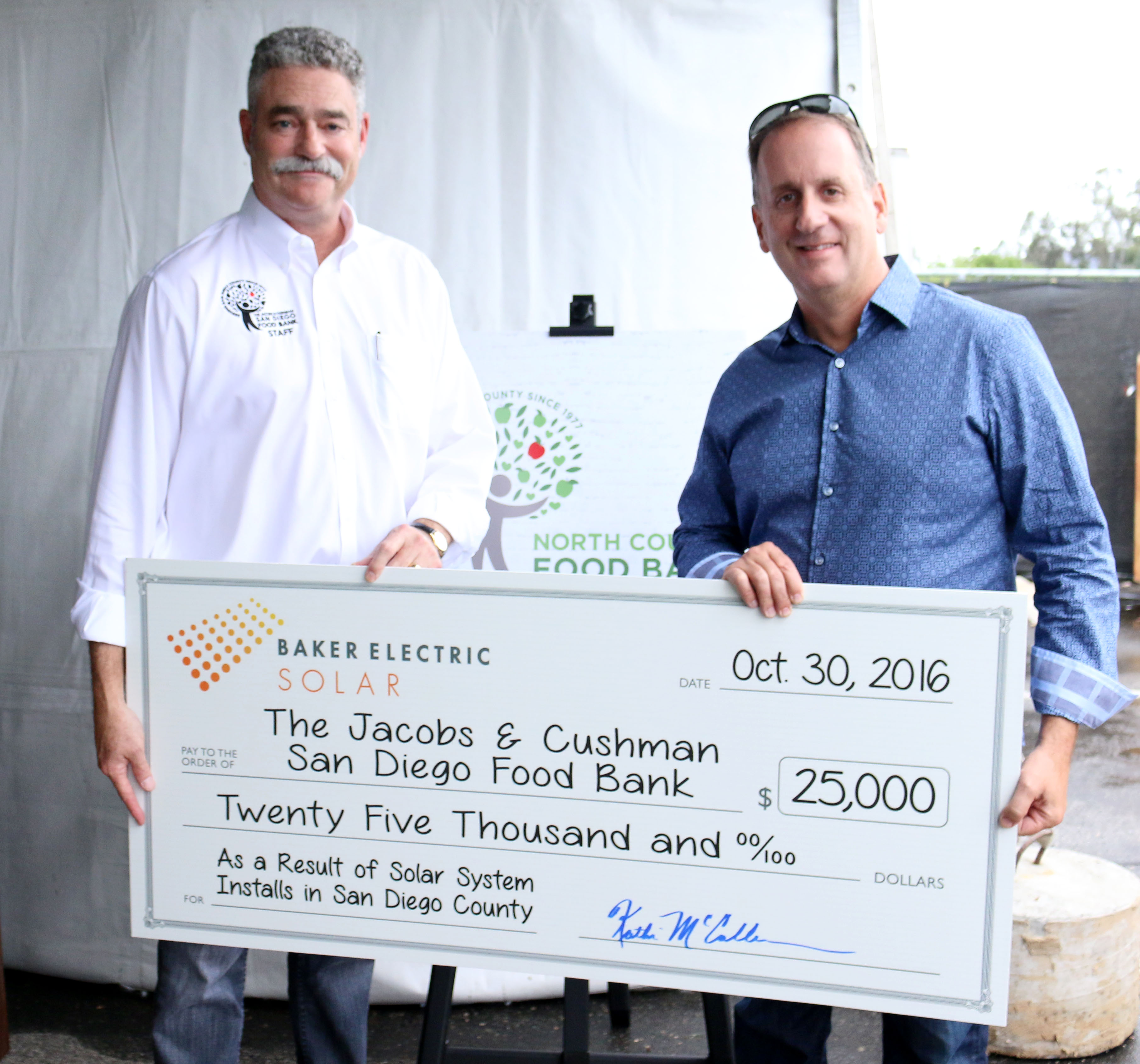 Baker Electric Solar president, Mike Teresso, presents James Floros, San Diego Food Bank CEO, with a $25,000 check in support of the North County Food Bank's hunger-relief programs.