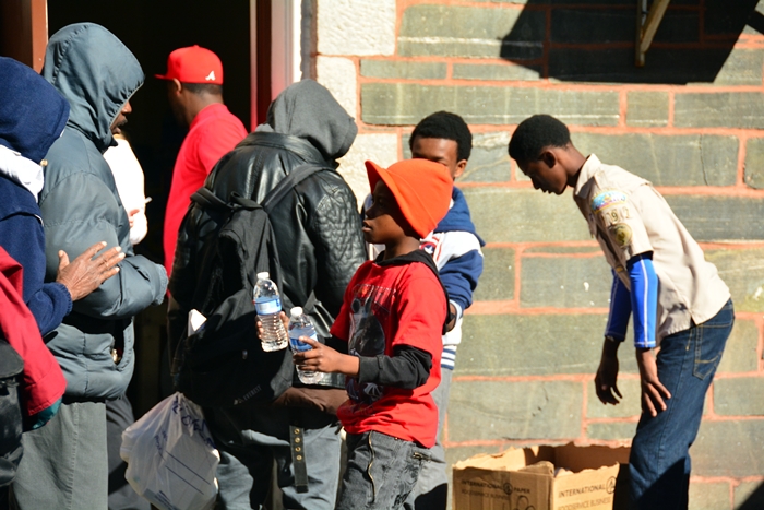 2014 Event A Young Volunteer Hands a Man a Bottle of Water