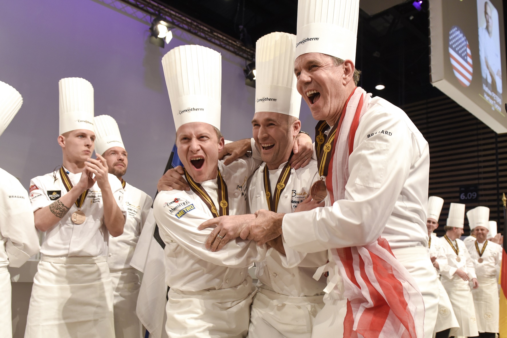 Team USA learns that they have just won the 2017 Bocuse d'Or in Lyon, France. From left to right: Team USA Coach Philip Tessier, Team USA Chef Mathew Peters & Team USA President Thomas Keller. (c) SIR