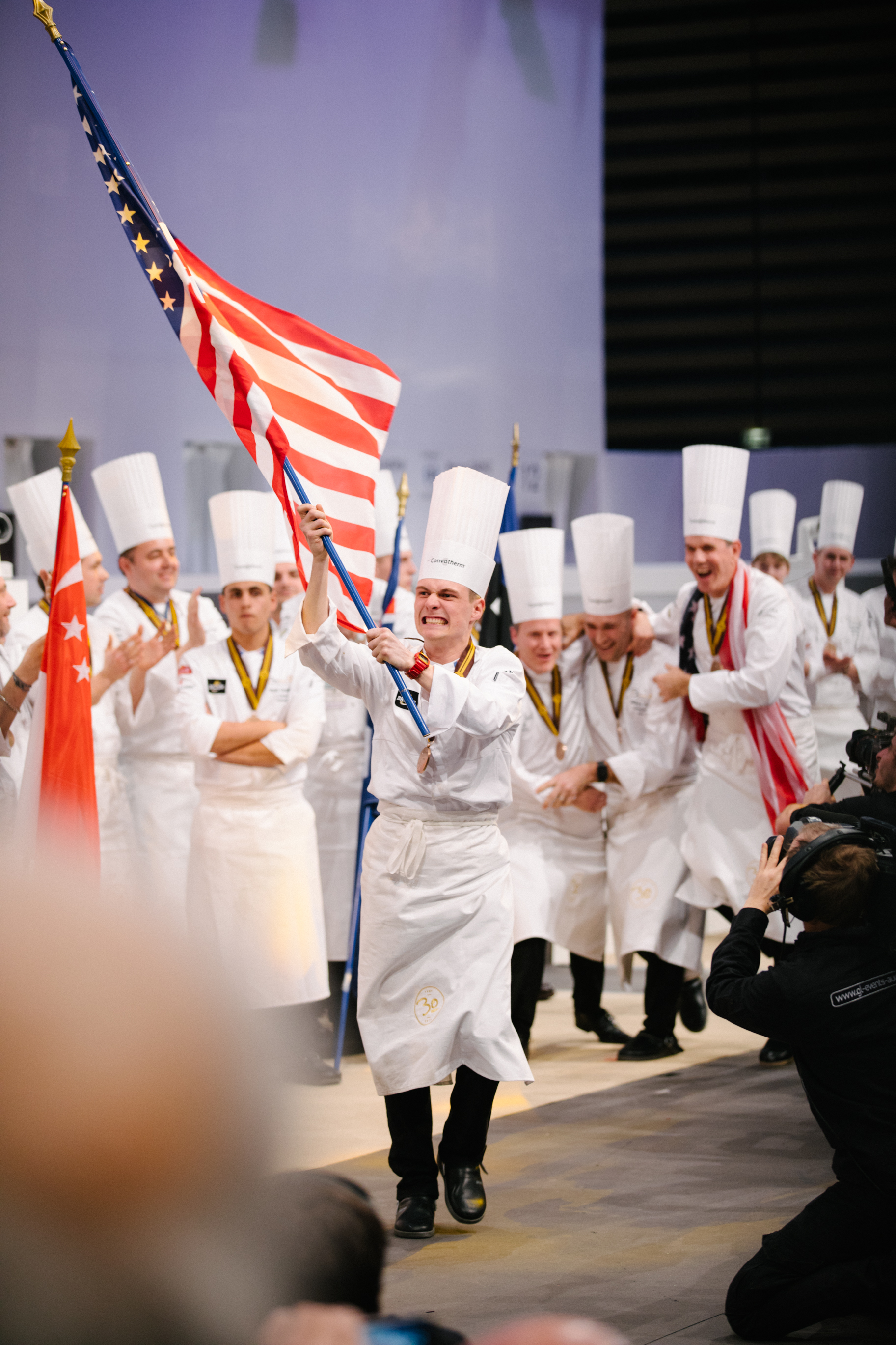 Team USA Commis Harrison Turone carries the American flag after his team was announced as the winner of the 2017 Bocuse d'Or. (c) SIRHA 2017