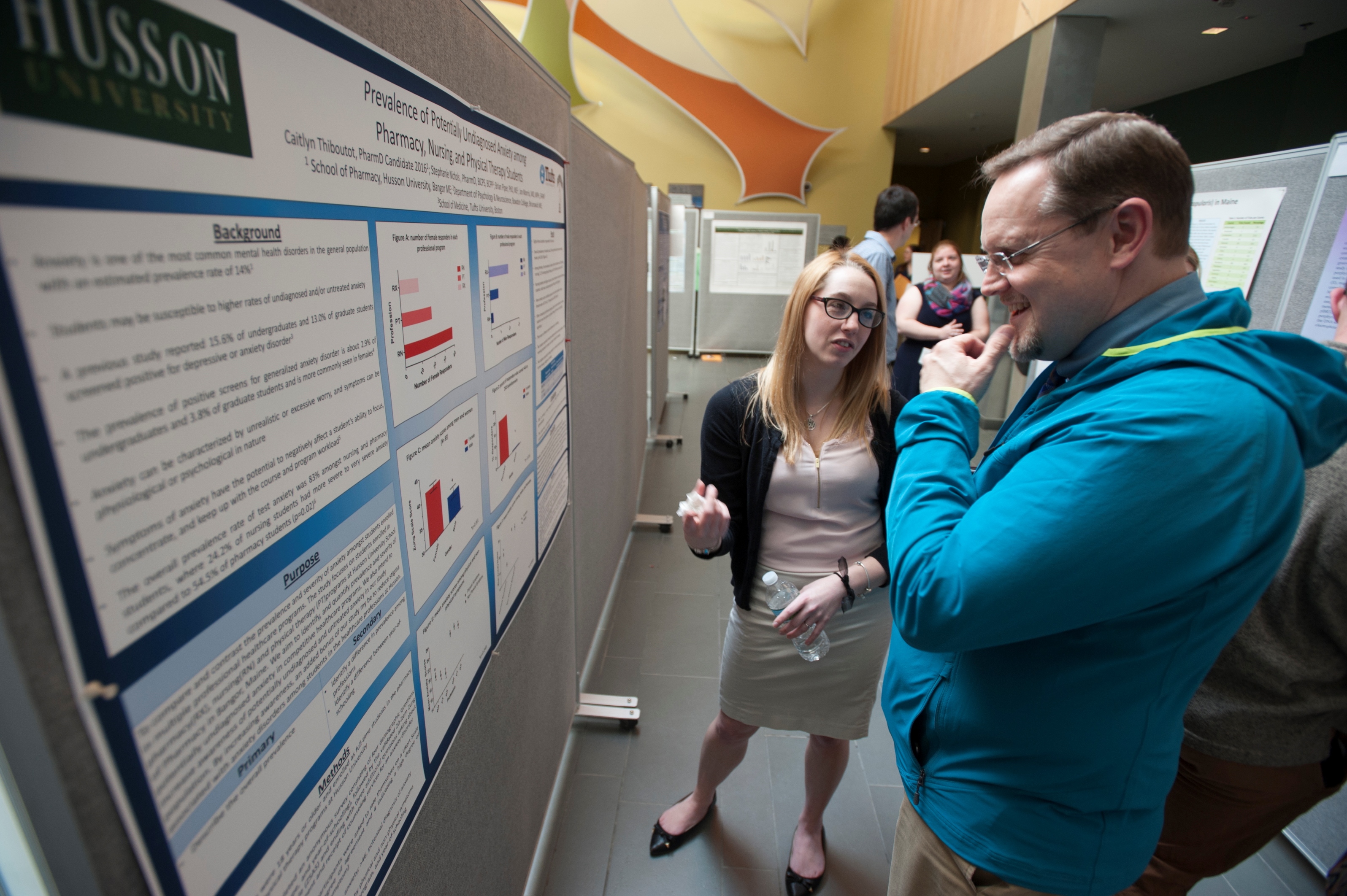 Husson University Vice President of Enrollment Jonathan Henry listens as a student explains her research into undiagnosed anxiety disorders.