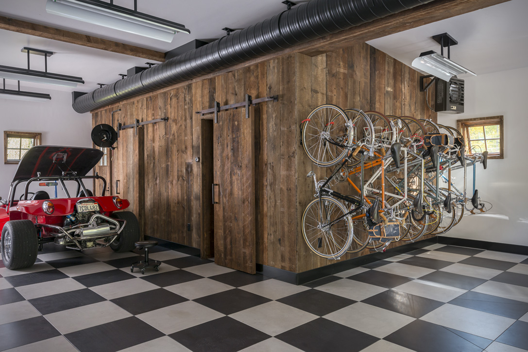 The ground floor garage of the guest barn features a graphic checkerboard tile floor and customized storage for the homeowners’ vintage cars and road bicycles (photo by Audrey Hall).