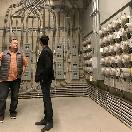 Jonas Villalba, VP of Project Development with Promise Energy, demonstrates the complexity of the installed conduit runs from Olympic's individual PV systems.