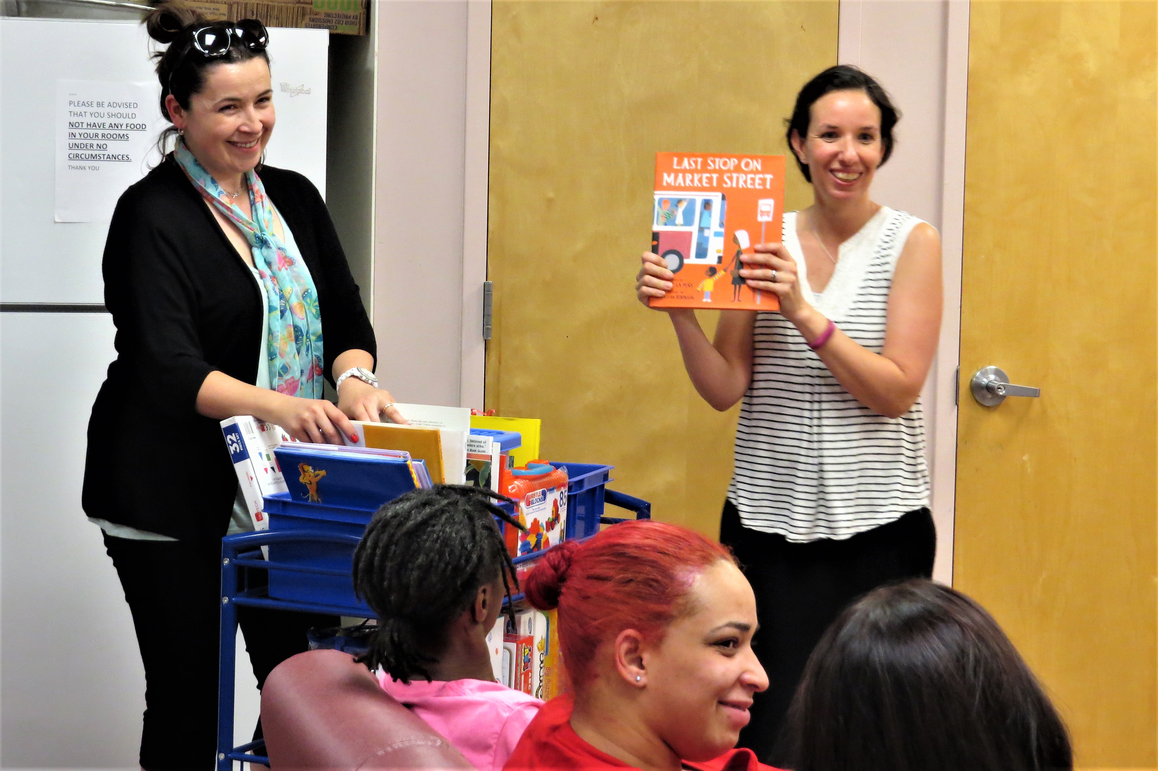 Facilitators from Passaic County Community College demonstrate ways that mothers who live at Eva’s Village can use library cart materials to support learning and bonding with their children.