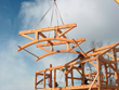 A parallel truss with curved bottom chords is "flown" into place by New Energy Works craftsmen.