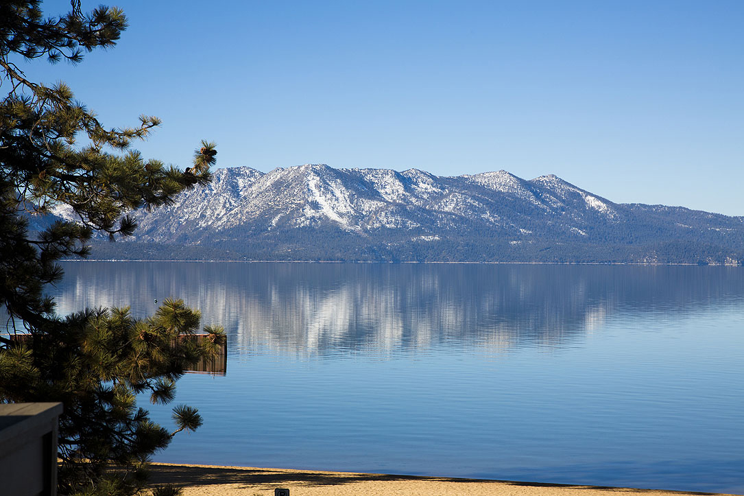 View from The Landing Resort & Spa’s rooftop deck embraces sandy Lakeside Beach, Lake Tahoe’s aquamarine waters and the Sierra Nevada Mountains beyond.