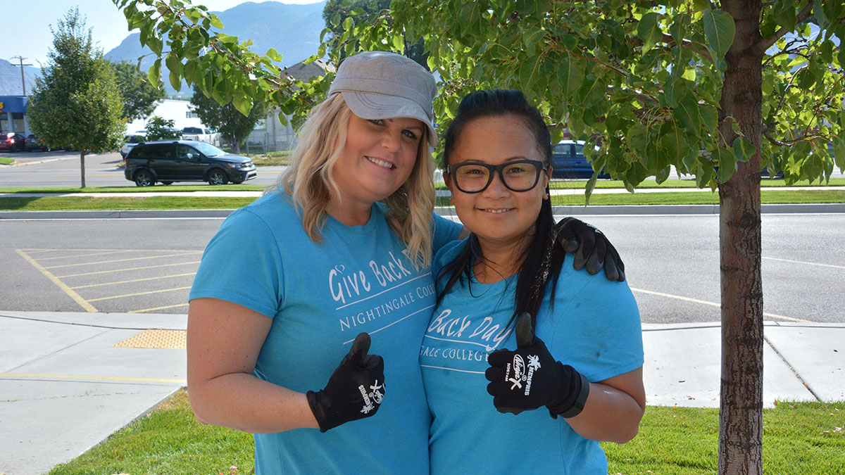 Two collaborators give a thumbs up after sprucing up the front lawn at  OWCAP-Head Start.