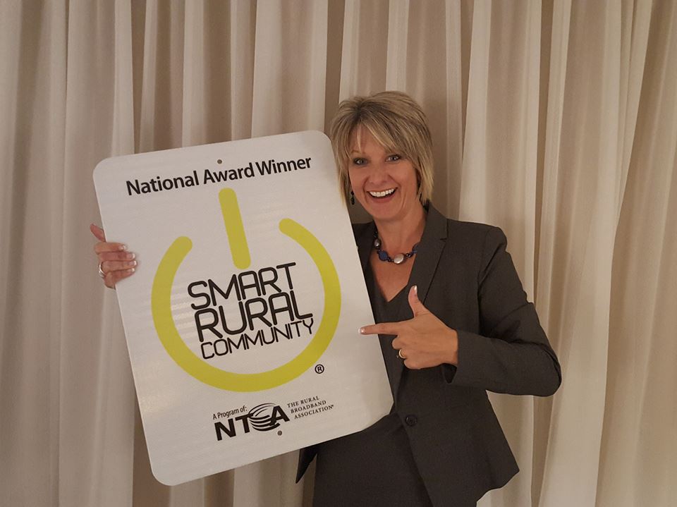 Marcie Boener, WCCTA, proudly showing off their new sign as a SMART RURAL Community.