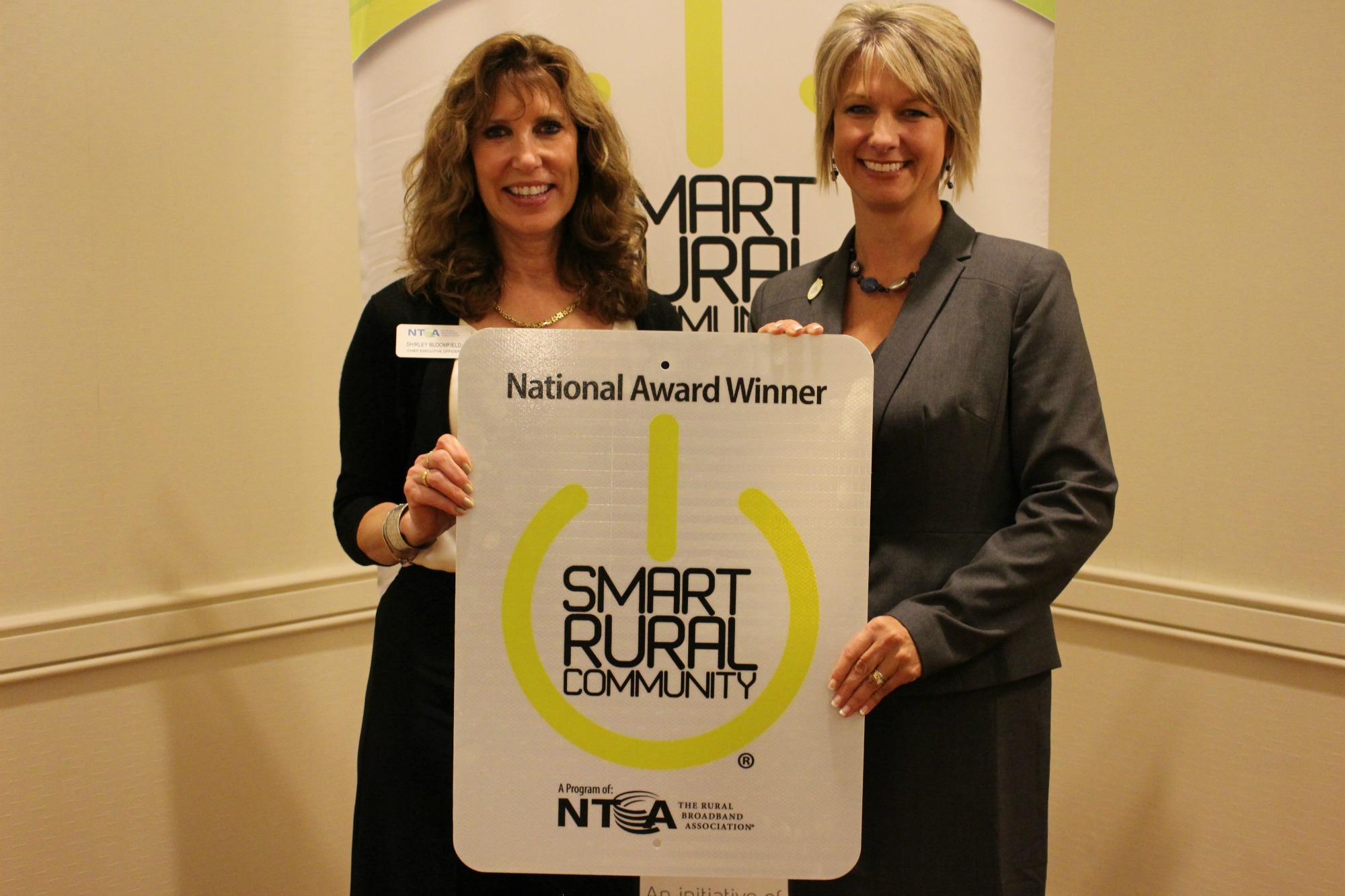 NTCA CEO Shirley Bloomfield and Marcie Boerner with WCCTA and the official sign to be displayed in the community