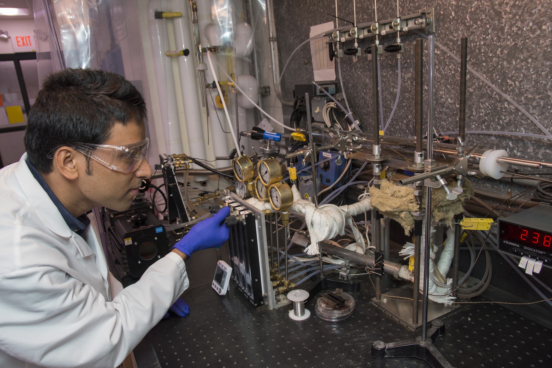 Binod Giri, a PhD student in mechanical engineering at Worcester Polytechnic Institute (WPI), adjusts an apparatus in the NanoEnergy Lab that uses flame-assisted sublimation to deposit thin films of p