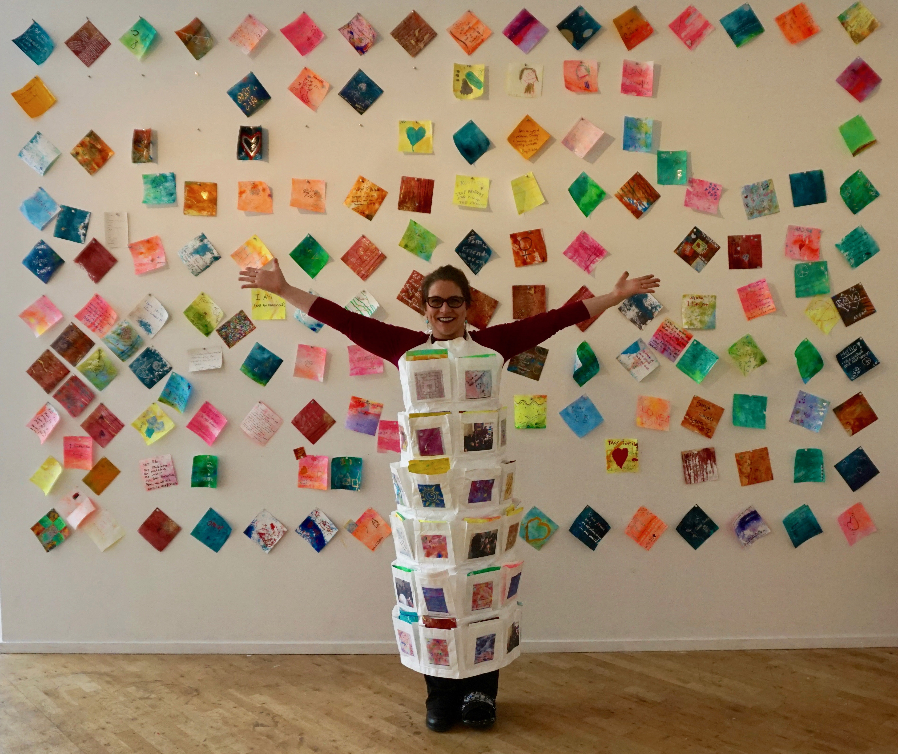 Artist, Anne Labovitz, wearing choices apron with 122 Conversation audience engagement tile pieces.
