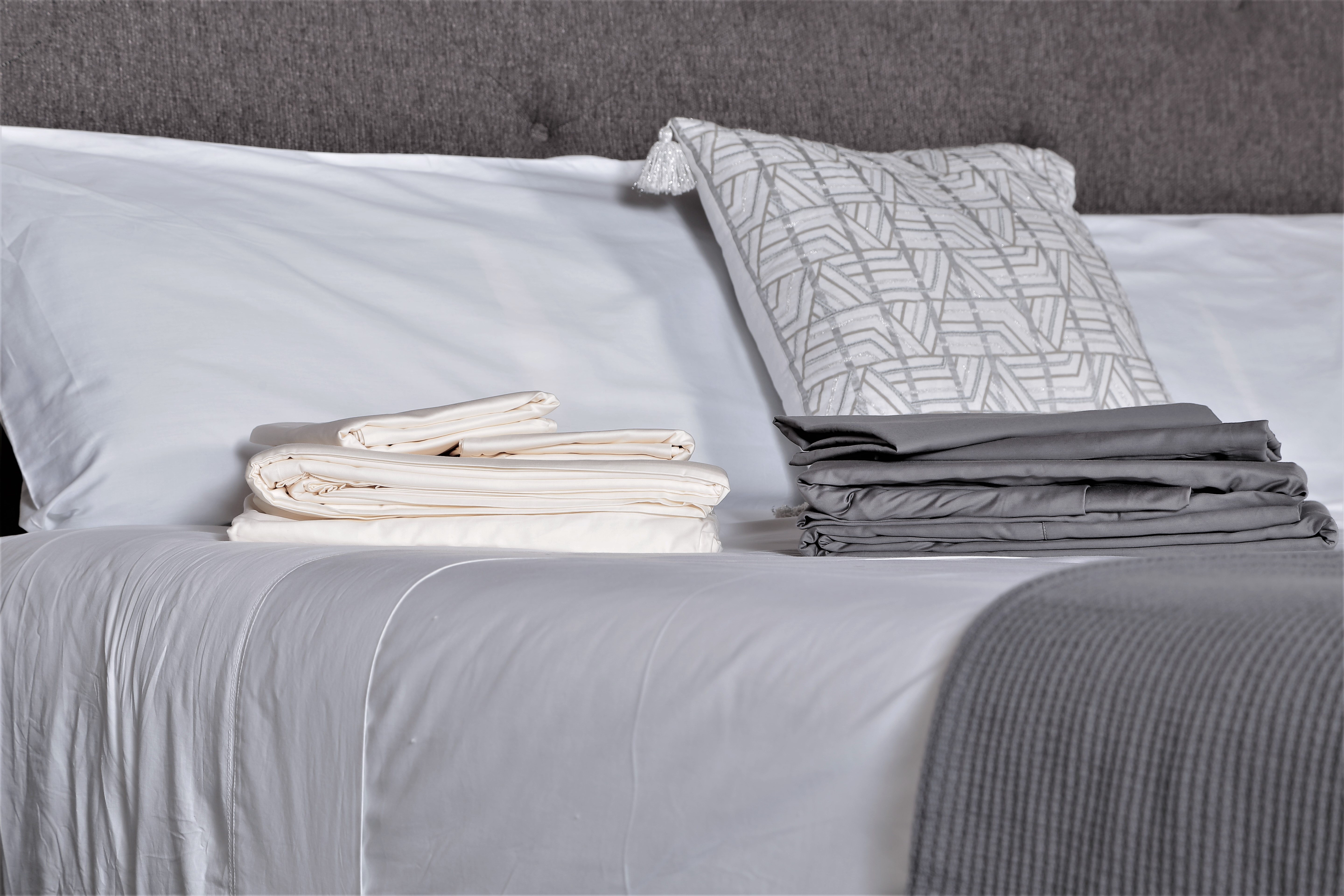 Grund bed with white grey sheets and grey throw