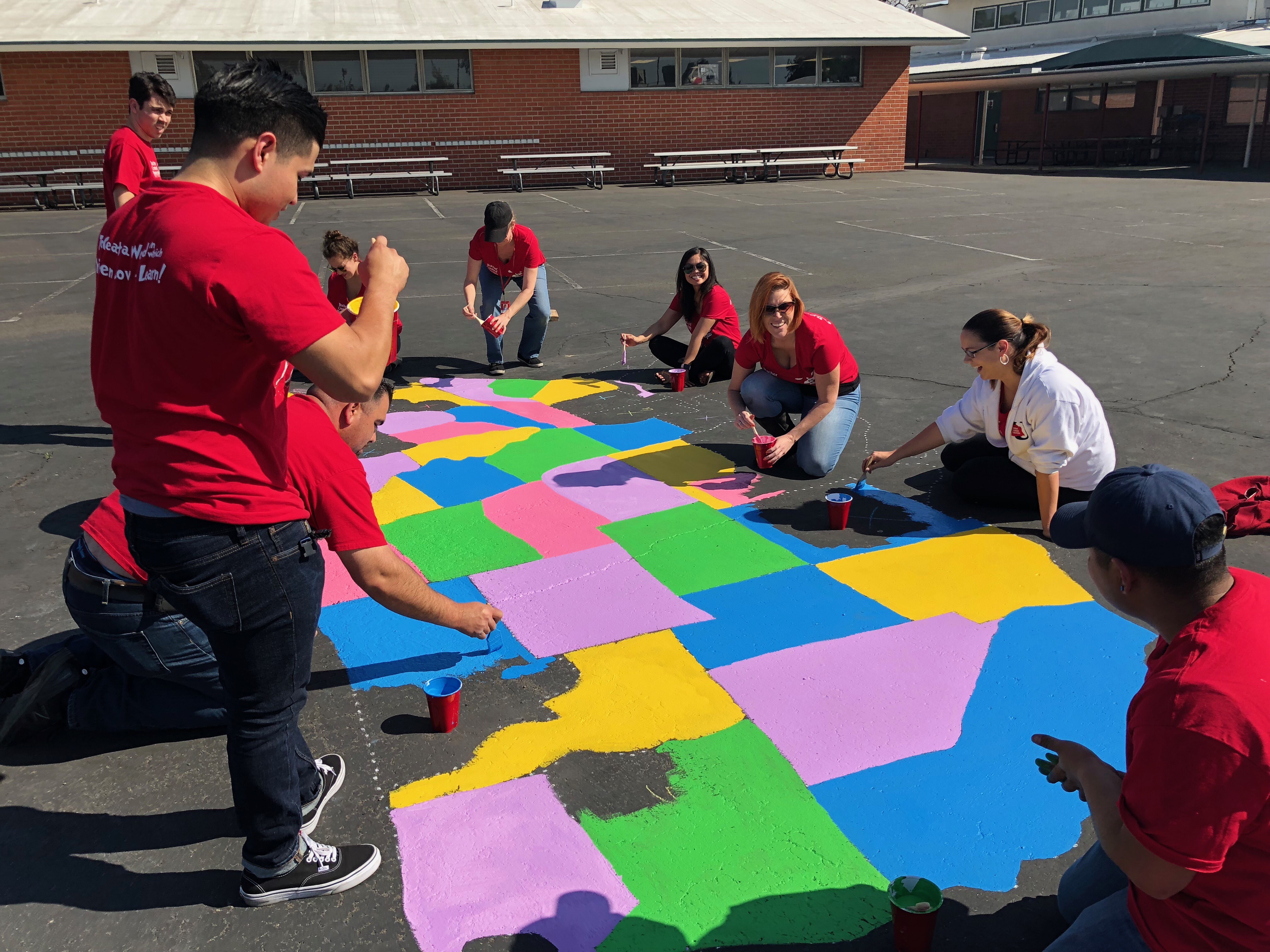 Teacher Created Materials staff paints the US map on the blacktop at Carl E. Gilbert Elementary School