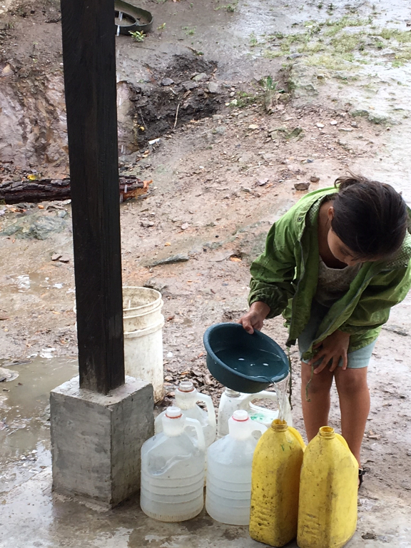 Honduran girl filling water containers.