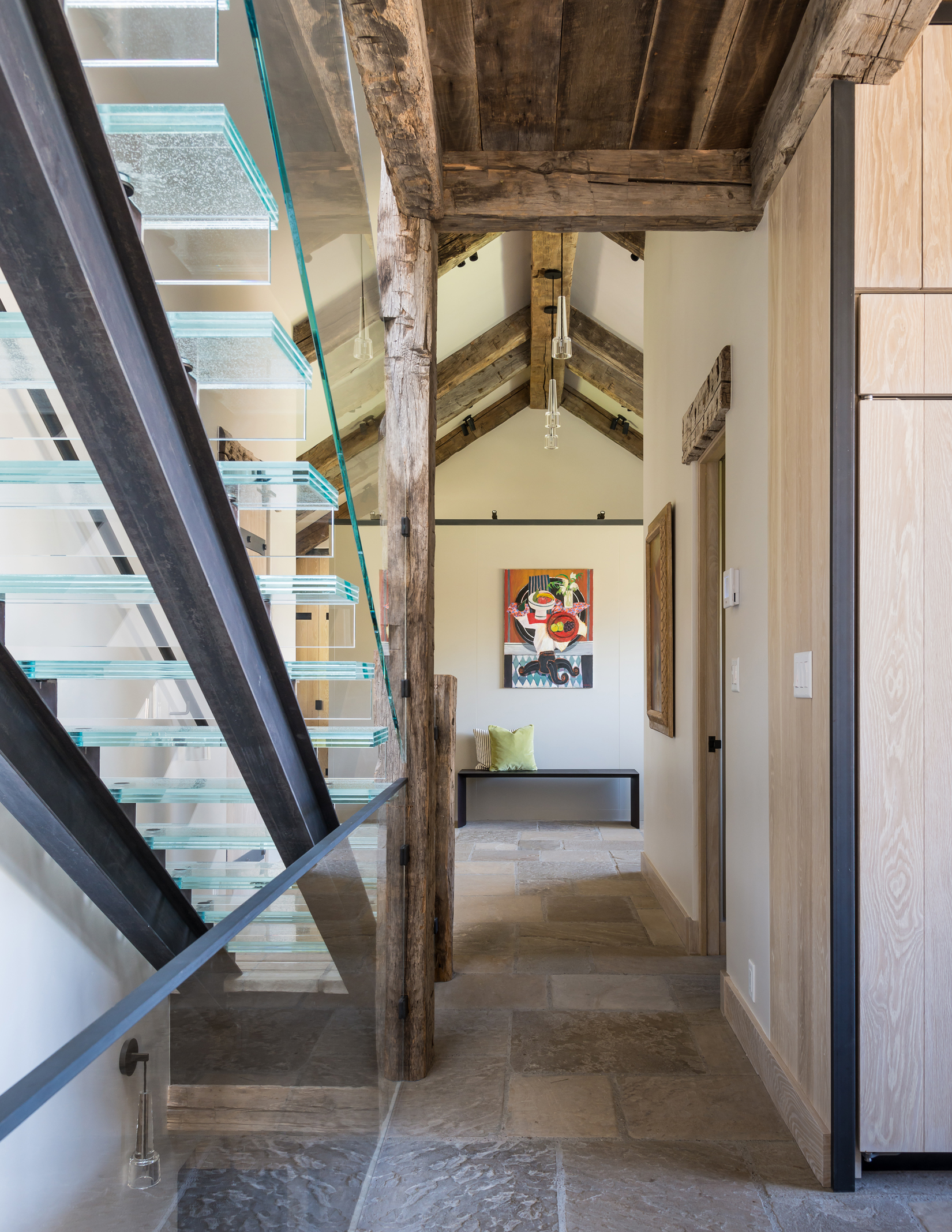 A floating glass stairway leading to the master bedroom gets regional grounding from weathered timbers in this Wyoming home by JLF Architects and Big-D Signature builders (photo by Audrey Hall).