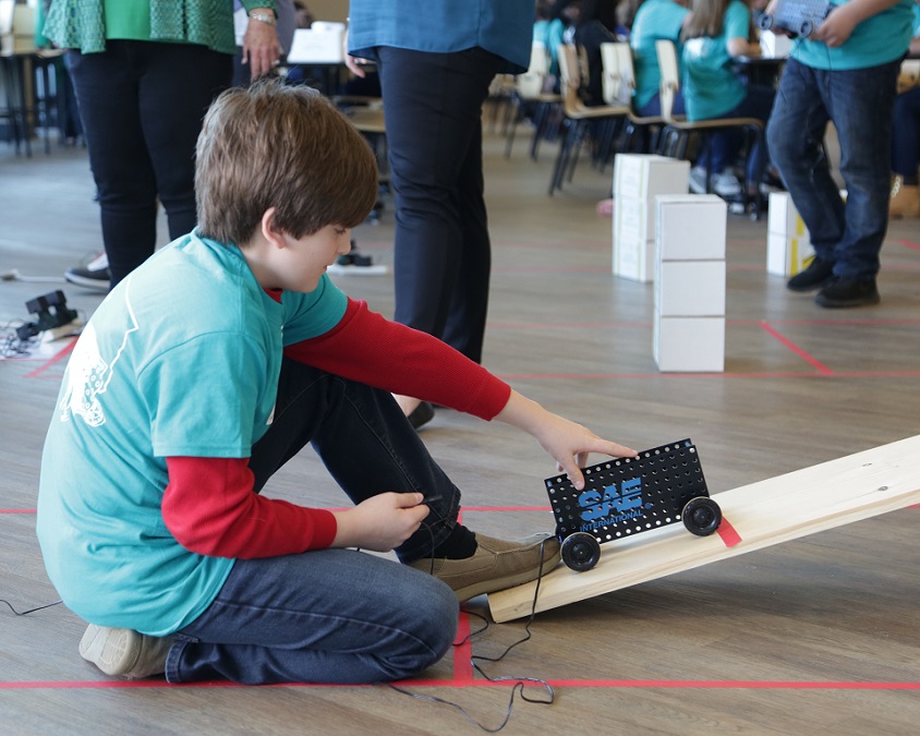 A student readies his car behind the starting line for the 15 degree ramp challenge.