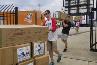 Volunteers carry Ashley HomeStore bed items to give to 100 Joliet area families through the company's Hope to Dream program.