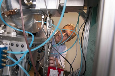 David Medich examines a vacuum pump contained in the neutron generator.