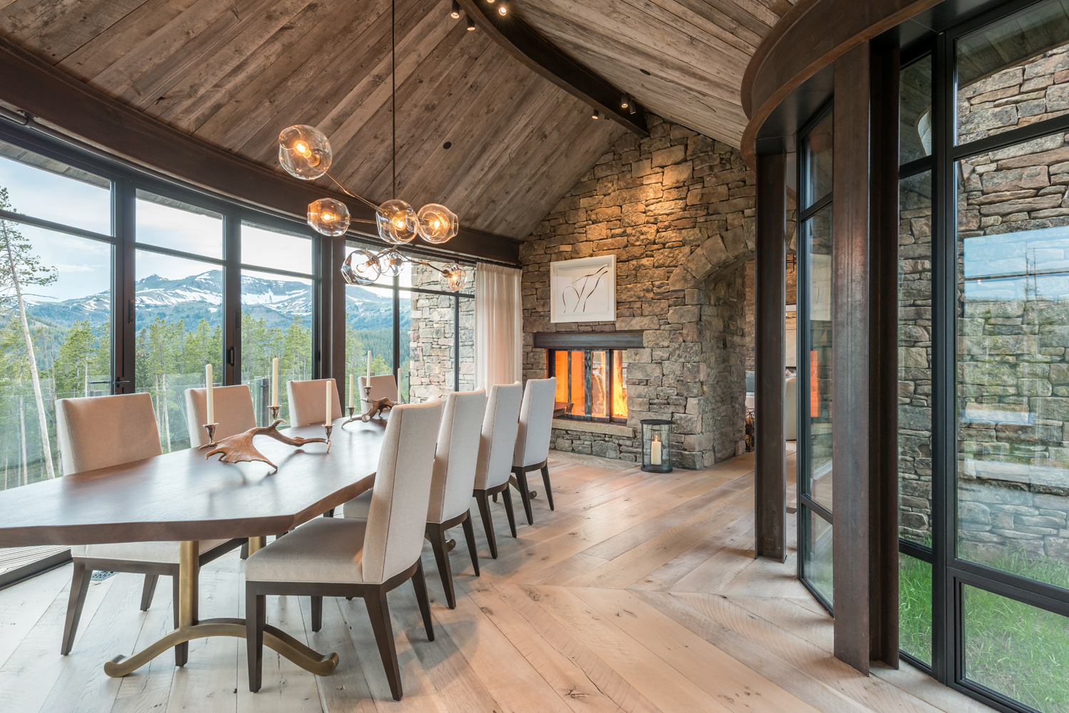 The curved glass-enclosed dining room, a signature design of JLF, frames mountain views and takes cues from rustic architectural materials in this Montana home (photo by Audrey Hall).
