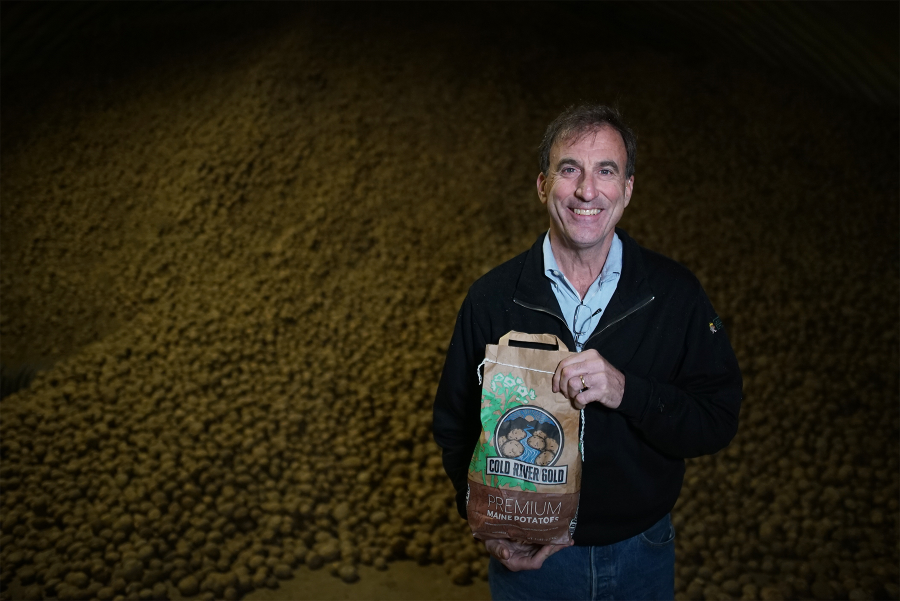Don Thibodeau, President of Green Thumb Farms in Fryeburg, Maine, holds a new bag of Cold River Gold potatoes.