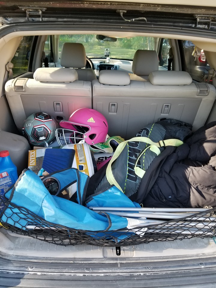A cargo area heaped with sports equipment, portable chairs and other items