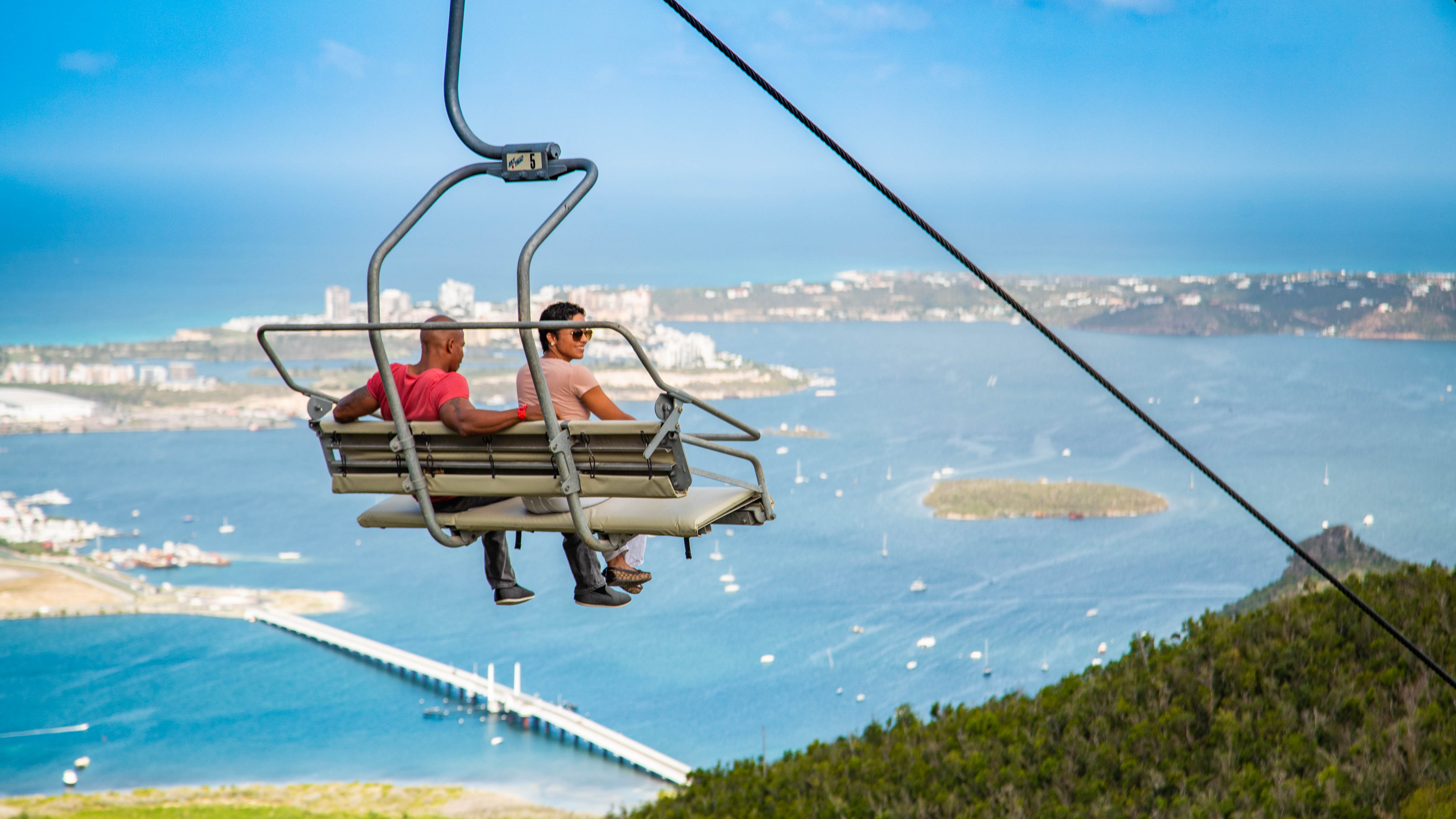 Sightseers relax and watch the beauty of St. Maarten unfold as they ascend on the Soualiga Sky Explorer at Rainforest Adventures Rockland Estate.