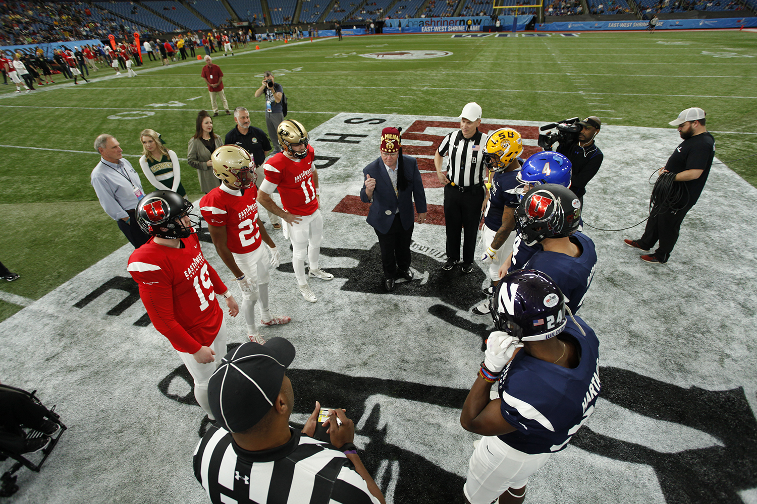 Team captains meet for the coin toss for the East-West Shrine Game. Flipping the coin is Imperial Potentate, Jim Cain.