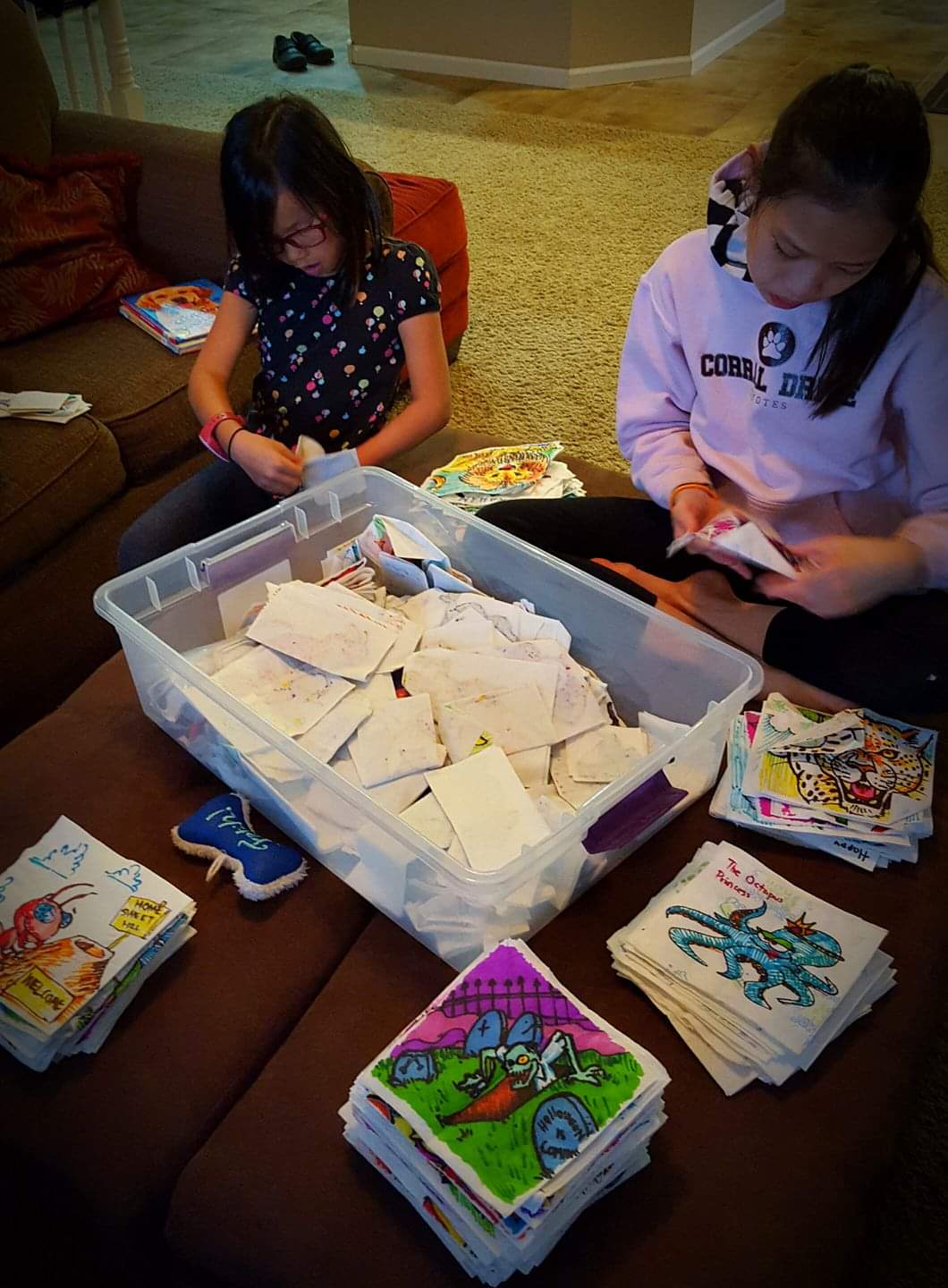 Math professor Travis Kolwaski's daughters Maia, 9, and Liliana, 13, look through the hundreds of napkin art creations he's drawn for them over the years.