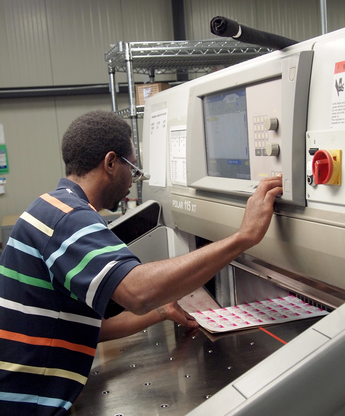 Tony Jones operates a guillotine paper cutting machine in the L.A.B. printing facility.