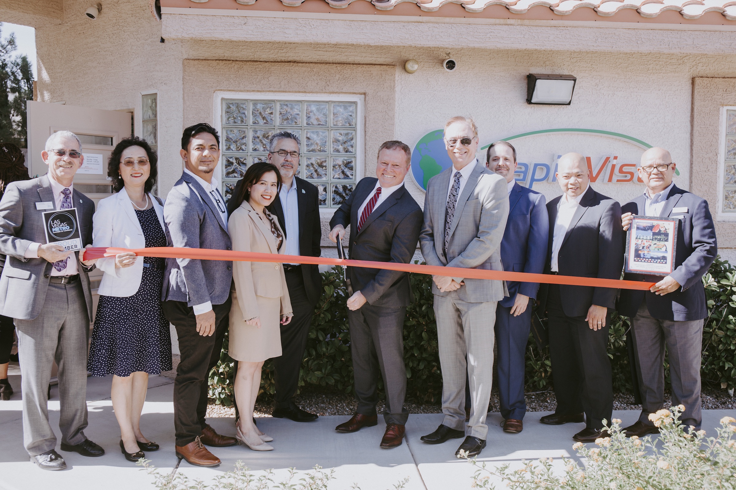Ben Ives (center), flanked by RapidVisa Staff and members of the Las Vegas Metro, Asian, and Latin Chambers of Commerce attend a ribbon cutting ceremony during RapidVisa’s 10th anniversary and grand o