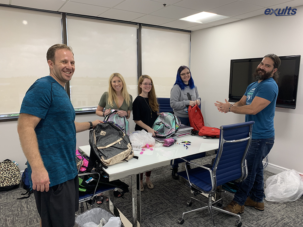 The Exults Internet Marketing Agency team assembling backpacks full of school supplies for the Broward Education Foundation's School Supplies Drive