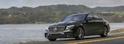 201 Mercedes-Benz E-Class exterior front fascia and drivers side going fast on a lakeside road