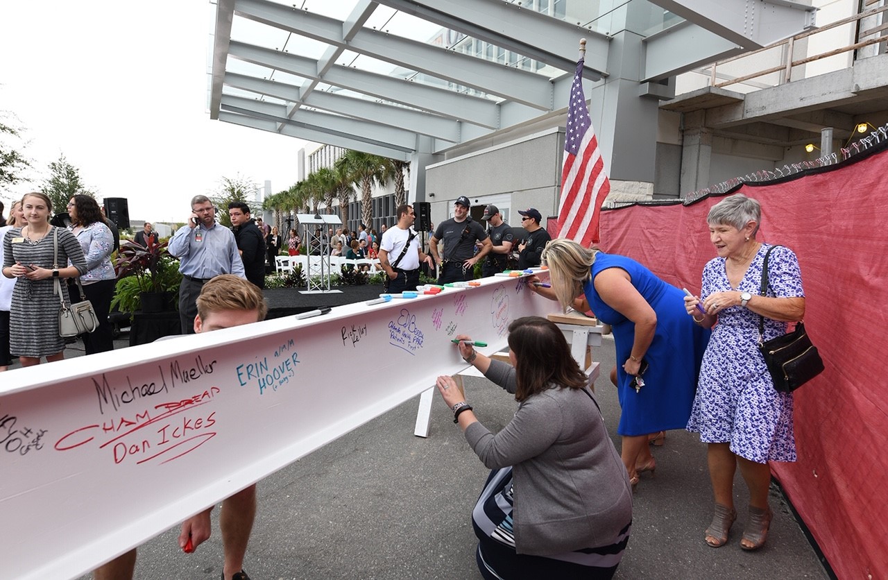 Event guests sign the facility's final beam.