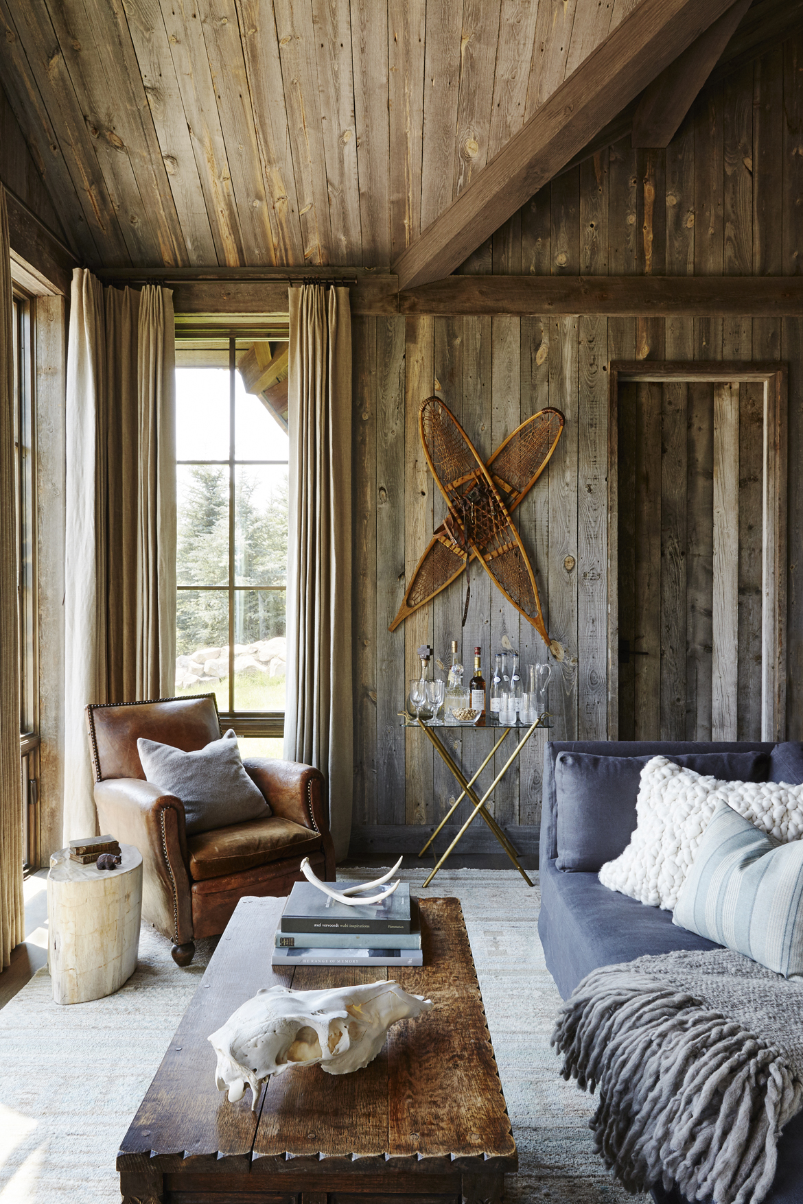 The rustic coziness in the living area of the WRJ-designed guest house plays on layers of texture such as the plush pillows, knotted throw and nubby woolen rug (photo by William Abranowicz).