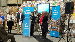 FPI Vice President Natha Dempsey awards the FPI Community Partnership grant to Kent County, Michigan, in front of recycling advertising featuring accepted foodservice packaging items.