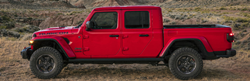Red 2020 Jeep Gladiator from showing driver side in front of field