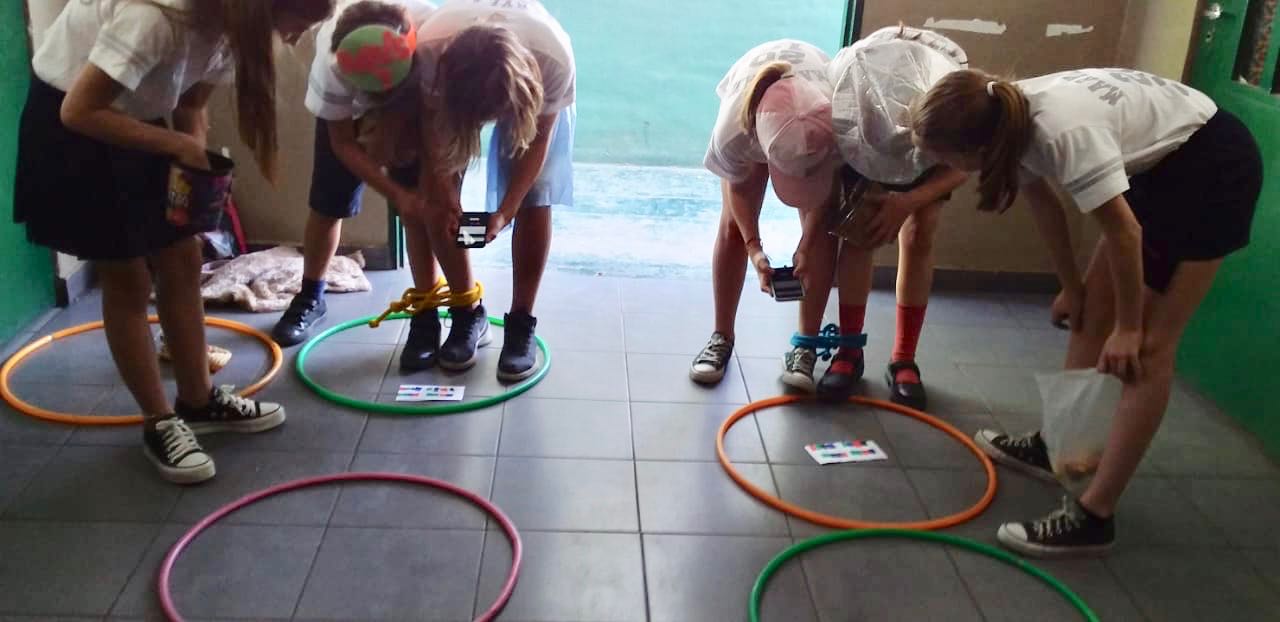 Students work in teams to play a math game with hoops and smartphones.