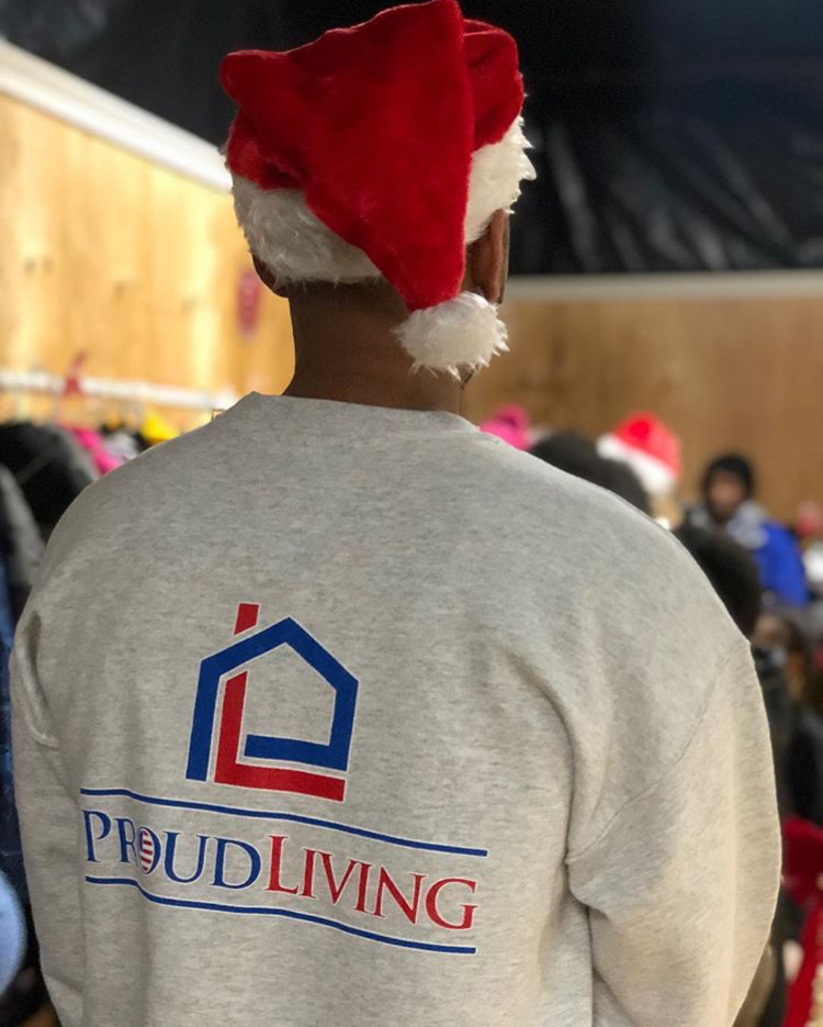 A ProudLiving staffer dons company attire and celebrates the season during the companyu2019s Coat and Toy Drive.