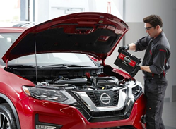 Image of a service technician installing a battery inside a Nissan vehicle