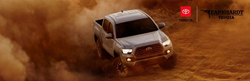 Gray 2020 Toyota Tacoma Kicking Up Dust in the Desert with Red, White and Black Earnhardt Toyota Logo in Upper Right Corner