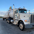 A semi tractor and vacuum equipped aluminum tanker is parked